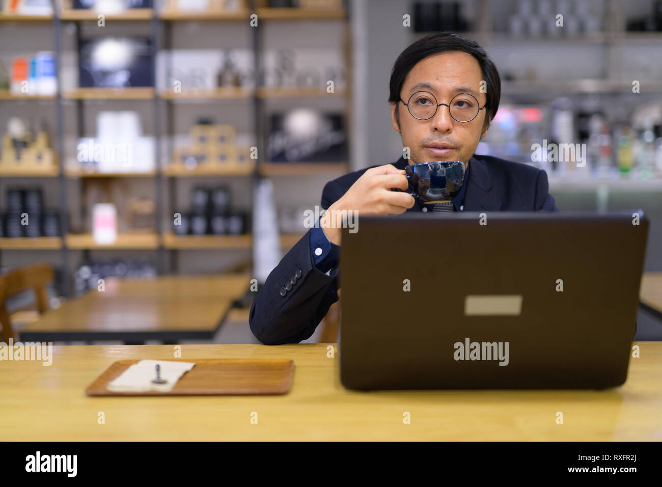 Imprenditore asiatico di bere il caffè mentre di pensare e di lavorare Foto Stock