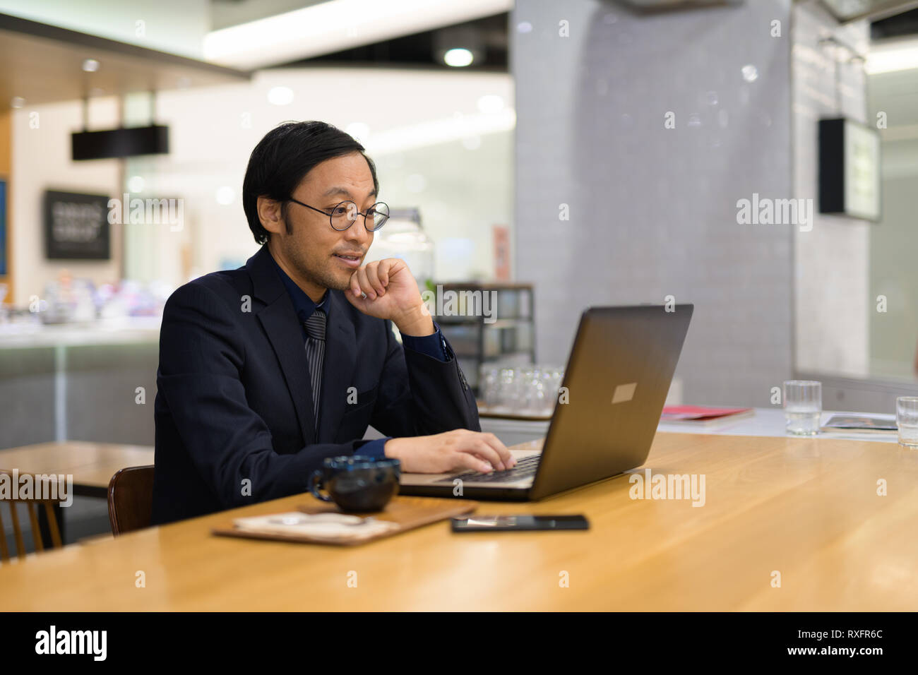 Happy businessman asiatici pensare mentre si lavora al coffee shop Foto Stock