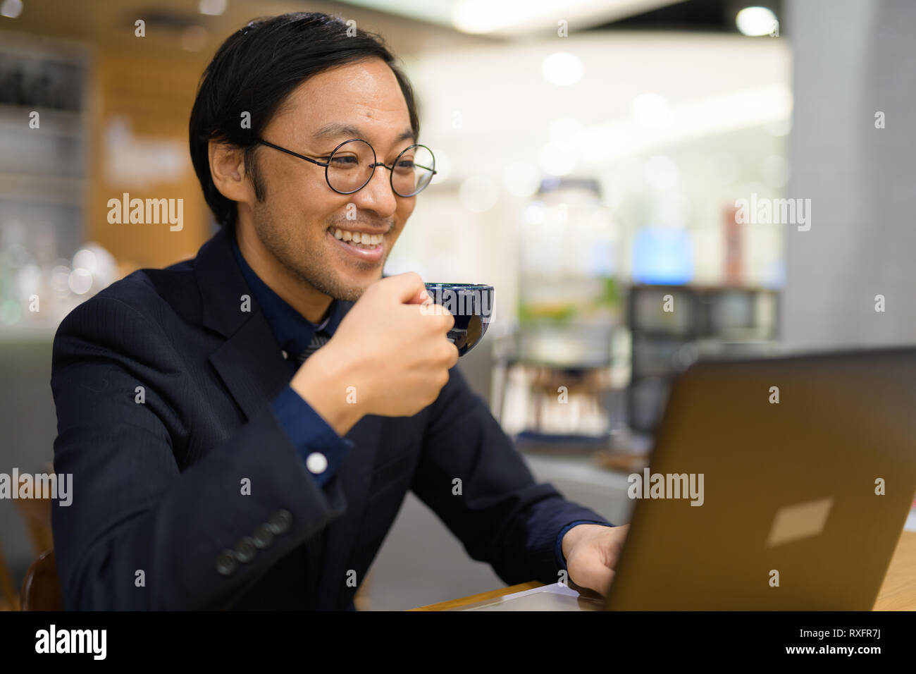 Happy businessman asiatica di bere il caffè mentre si lavora al coffee shop Foto Stock