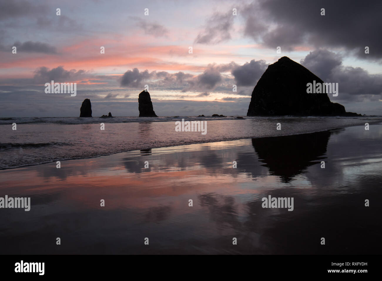 Haystack Rock e gli aghi al tramonto, Cannon Beach, Oregon Foto Stock