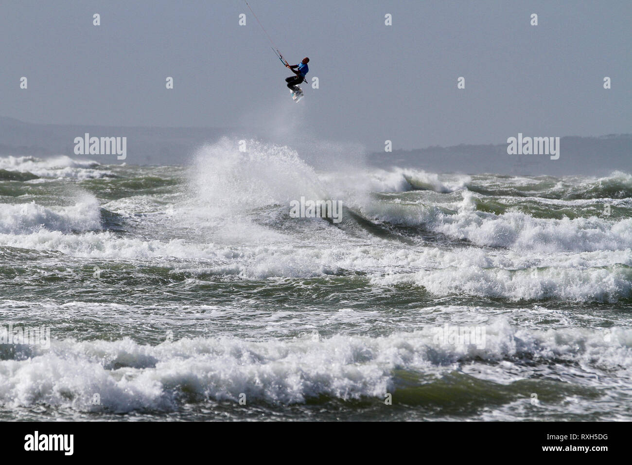 West Strand, West Wittering, Sussex, Regno Unito. Il 10 marzo 2019. Severe gales lungo la costa sud di oggi con raffiche di oltre 60 km/h. Quattro volte campione britannico Kitesurfer Lewis Crathern, famosa per il suo salto kitesurfer oltre il molo di Brighton, in azione a 2XS sport acquatici a West Wittering beach in West Sussex. Credito: James jagger/Alamy Live News Foto Stock