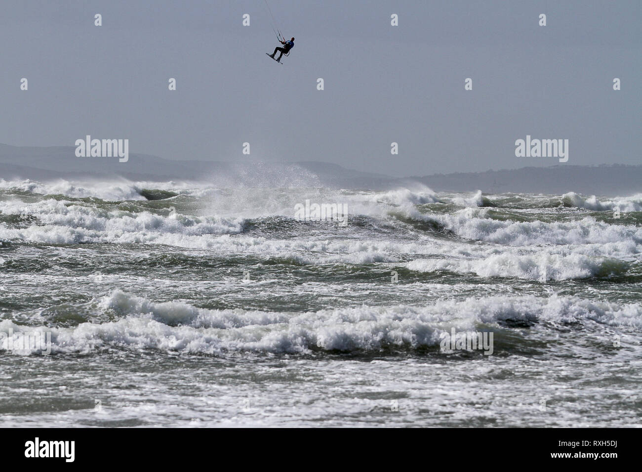 West Strand, West Wittering, Sussex, Regno Unito. Il 10 marzo 2019. Severe gales lungo la costa sud di oggi con raffiche di oltre 60 km/h. Quattro volte campione britannico Kitesurfer Lewis Crathern, famosa per il suo salto kitesurfer oltre il molo di Brighton, in azione a 2XS sport acquatici a West Wittering beach in West Sussex. Credito: James jagger/Alamy Live News Foto Stock