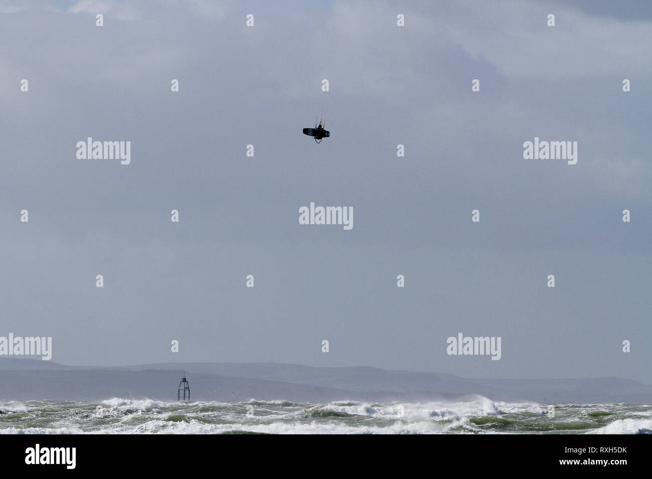 West Strand, West Wittering, Sussex, Regno Unito. Il 10 marzo 2019. Severe gales lungo la costa sud di oggi con raffiche di oltre 60 km/h. Quattro volte campione britannico Kitesurfer Lewis Crathern, famosa per il suo salto kitesurfer oltre il molo di Brighton, in azione a 2XS sport acquatici a West Wittering beach in West Sussex. Credito: James jagger/Alamy Live News Foto Stock