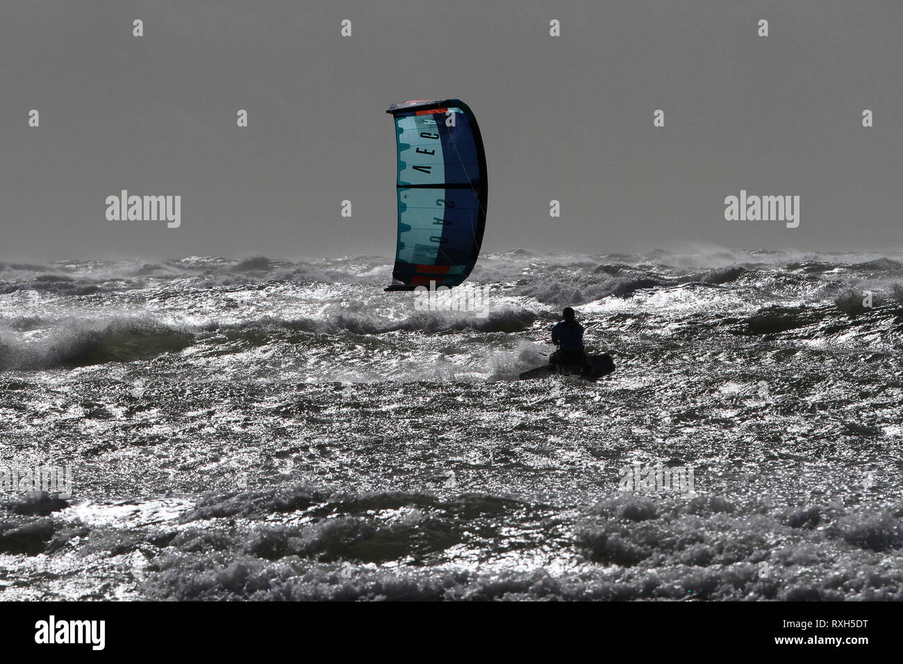 West Strand, West Wittering, Sussex, Regno Unito. Il 10 marzo 2019. Severe gales lungo la costa sud di oggi con raffiche di oltre 60 km/h. Quattro volte campione britannico Kitesurfer Lewis Crathern, famosa per il suo salto kitesurfer oltre il molo di Brighton, in azione a 2XS sport acquatici a West Wittering beach in West Sussex. Credito: James jagger/Alamy Live News Foto Stock