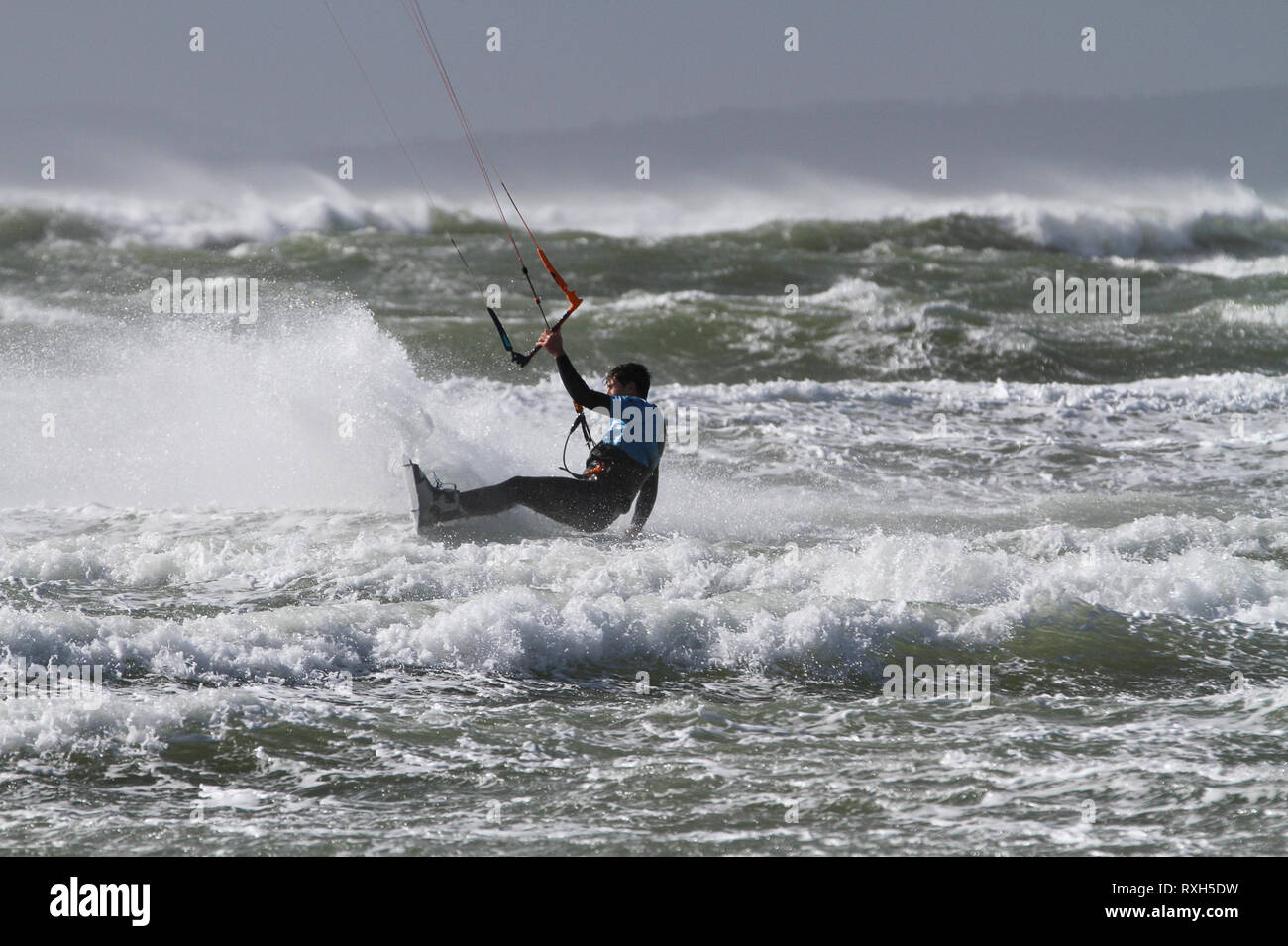 West Strand, West Wittering, Sussex, Regno Unito. Il 10 marzo 2019. Severe gales lungo la costa sud di oggi con raffiche di oltre 60 km/h. Cinque volte PKRA Kitesurf Campione del Mondo, Aaron Hadlow, in azione a 2XS sport acquatici a West Wittering beach in West Sussex. Aaron è da Hayling Island e ha vinto due volte il Red Bull re della concorrenza aria in Sud Africa Credito: James jagger/Alamy Live News Foto Stock