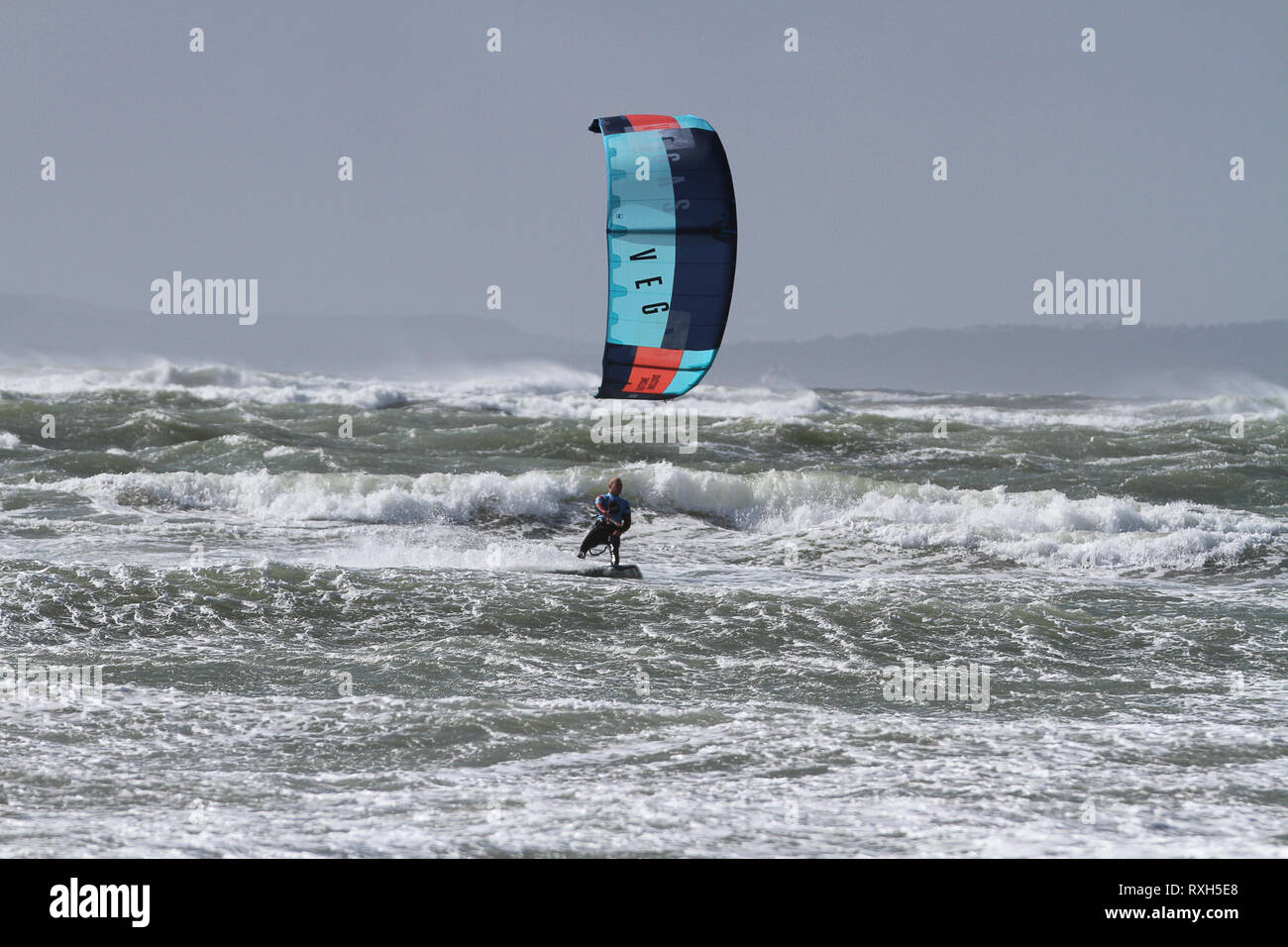 West Strand, West Wittering, Sussex, Regno Unito. Il 10 marzo 2019. Severe gales lungo la costa sud di oggi con raffiche di oltre 60 km/h. Quattro volte campione britannico Kitesurfer Lewis Crathern, famosa per il suo salto kitesurfer oltre il molo di Brighton, in azione a 2XS sport acquatici a West Wittering beach in West Sussex. Credito: James jagger/Alamy Live News Foto Stock