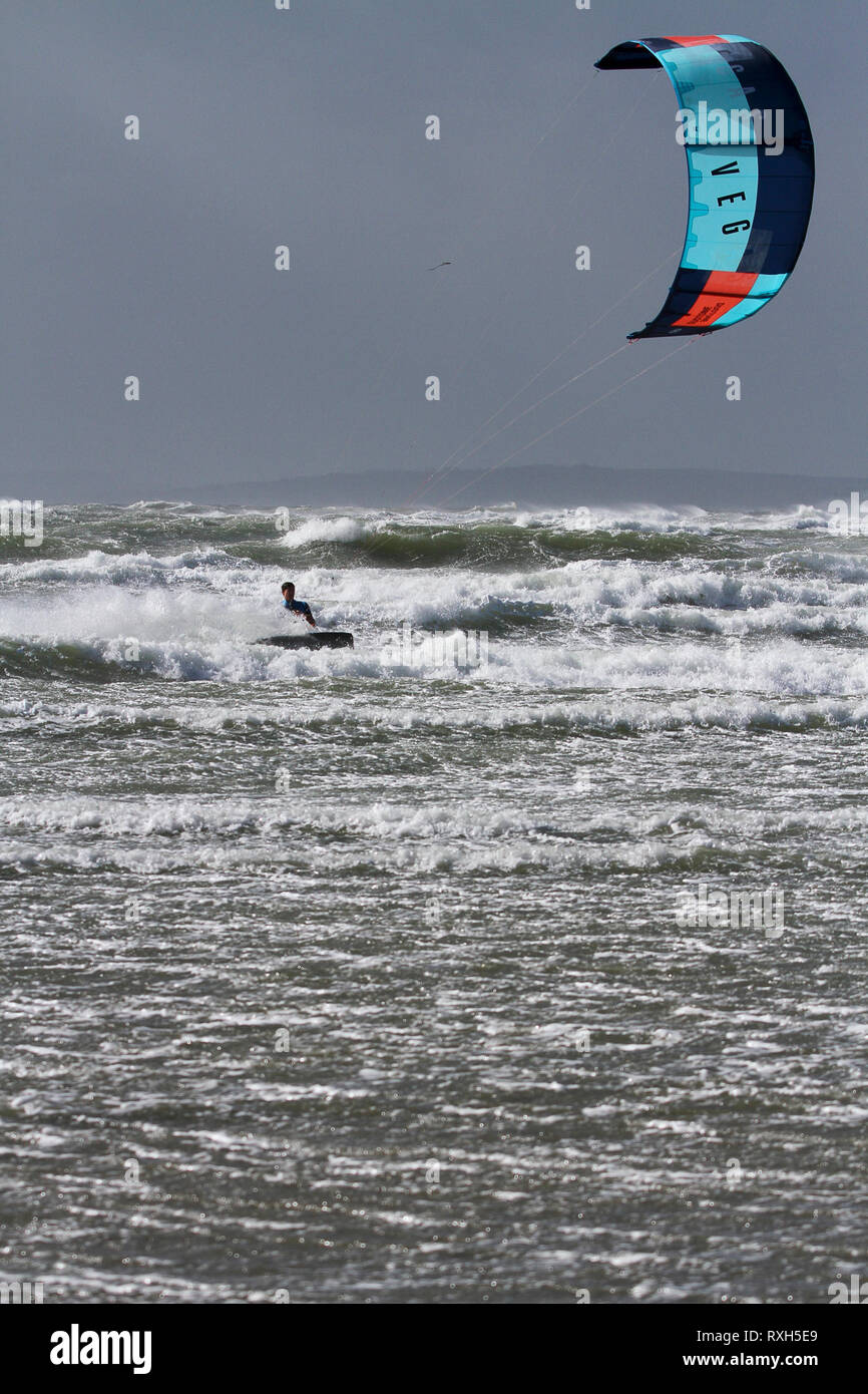 West Strand, West Wittering, Sussex, Regno Unito. Il 10 marzo 2019. Severe gales lungo la costa sud di oggi con raffiche di oltre 60 km/h. Cinque volte PKRA Kitesurf Campione del Mondo, Aaron Hadlow, in azione a 2XS sport acquatici a West Wittering beach in West Sussex. Aaron è da Hayling Island e ha vinto due volte il Red Bull re della concorrenza aria in Sud Africa Credito: James jagger/Alamy Live News Foto Stock