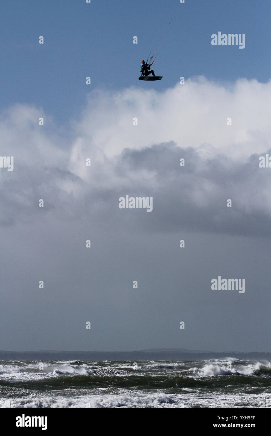 West Strand, West Wittering, Sussex, Regno Unito. Il 10 marzo 2019. Severe gales lungo la costa sud di oggi con raffiche di oltre 60 km/h. Quattro volte campione britannico Kitesurfer Lewis Crathern, famosa per il suo salto kitesurfer oltre il molo di Brighton, in azione a 2XS sport acquatici a West Wittering beach in West Sussex. Credito: James jagger/Alamy Live News Foto Stock