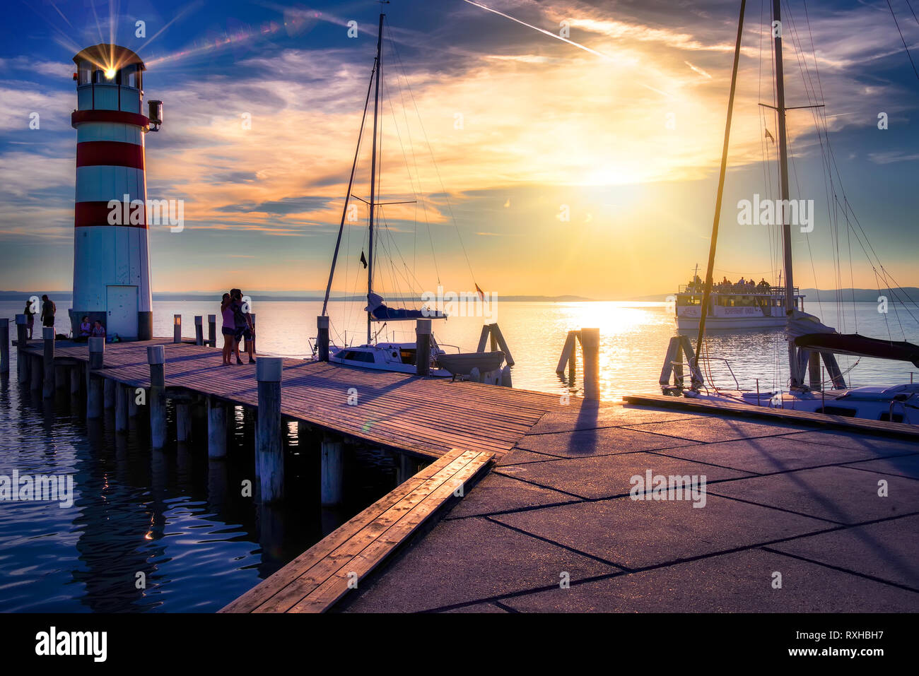 Austria, Podersdorf, 09/12/2018: faro presso il lago di Neusiedl al tramonto con una imbarcazione turistica tornando alla porta.Podersdorf am See è una città di mercato Foto Stock