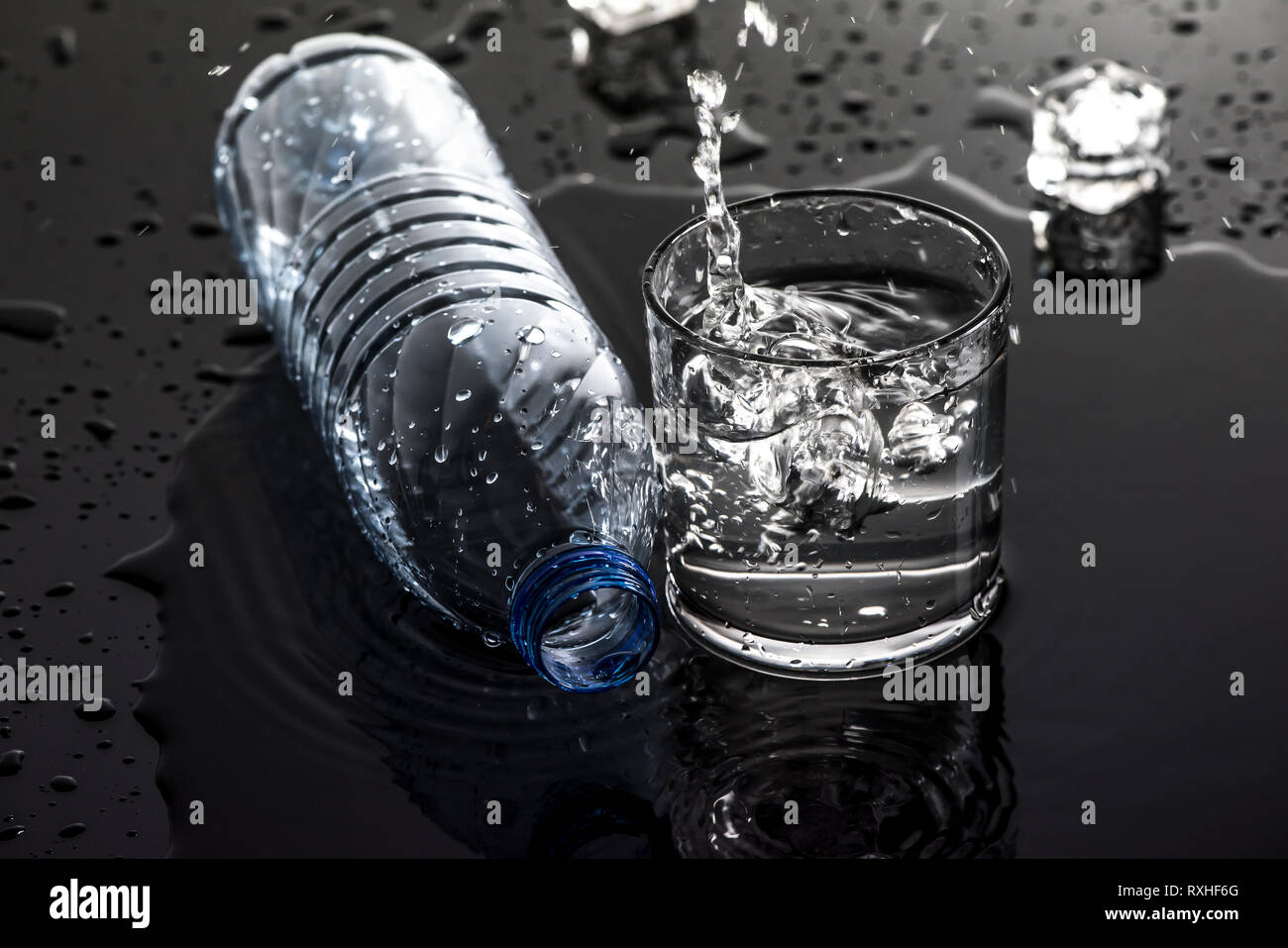 Un bicchiere di acqua con le bottiglie di plastica vuote Foto Stock