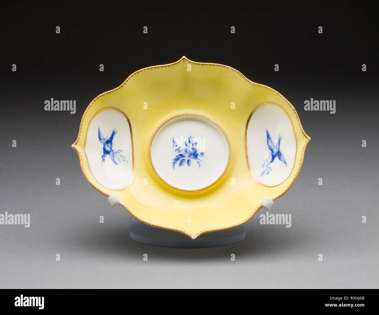 Supporto per una pentola di senape. Vincennes manifattura di porcellana; francese, fondata 1740 (noto come Sevres dal 1756); dipinta da André-Vincent Vielliard (francese, 1717-90, 1752-90 attivo). Data: 1751-1752. Dimensioni: 3,6 x 13,7 x 17,4 cm (1 3/8 x 5 3/8 x 6 13/16 in.). Soffice pasta di porcellana, massa giallo, Monocromatico blu smalto, e doratura. Origine: Vincennes. Museo: Chicago Art Institute. Autore: Manufacture de Porcelaine De Vincennes. Foto Stock
