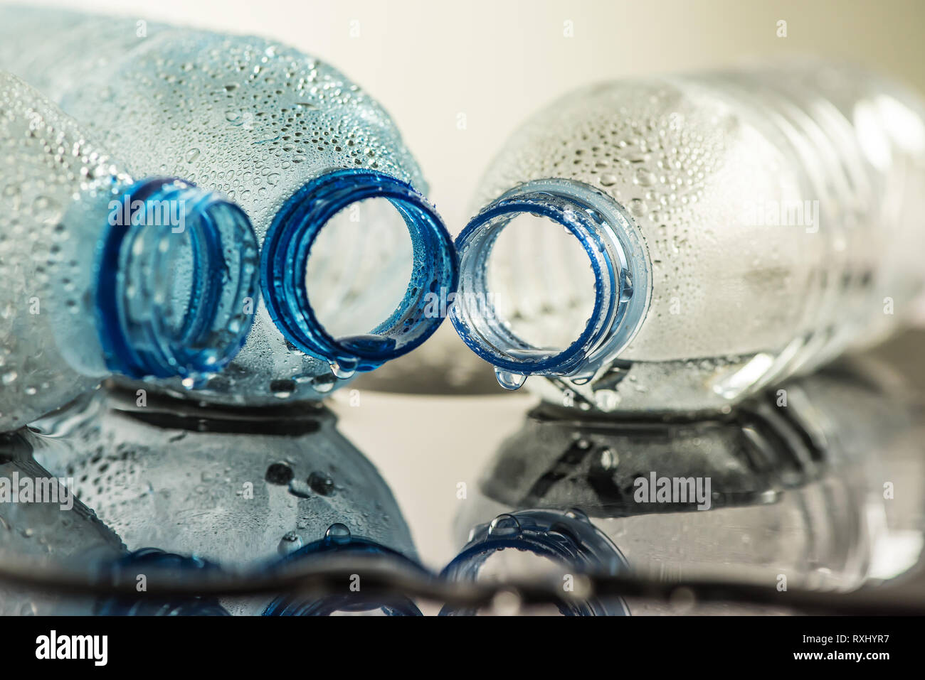 Sfondo bagnato con un bicchiere di acqua e le bottiglie di plastica vuote Foto Stock