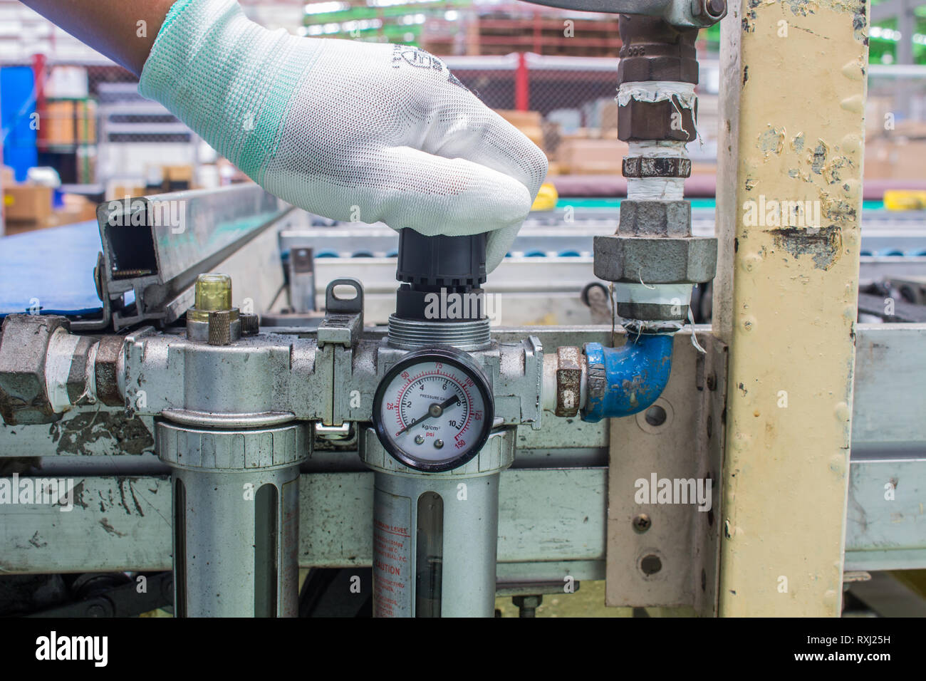La mano del tecnico regolare l'impostazione della pressione del vento sul regolatore. Nel sistema pneumatico Foto Stock