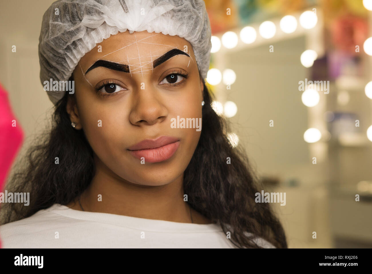 Bellezza procedura per la correzione della forma delle sopracciglia in spa salone. Faccia di razza mista donna con il markup di perfetta forma delle sopracciglia. Foto Stock