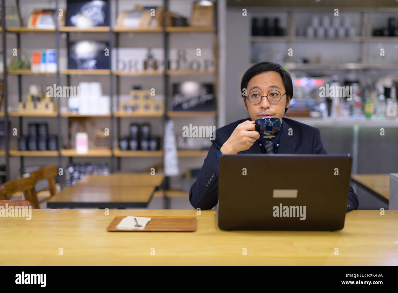 Considerato imprenditore asiatico di bere il caffè mentre si lavora Foto Stock