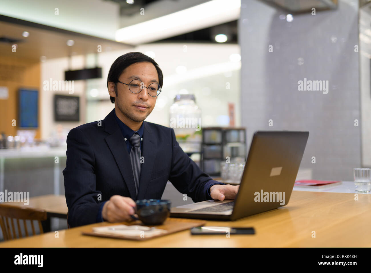 Imprenditore asiatici utilizzando laptop all'interno del coffee shop Foto Stock