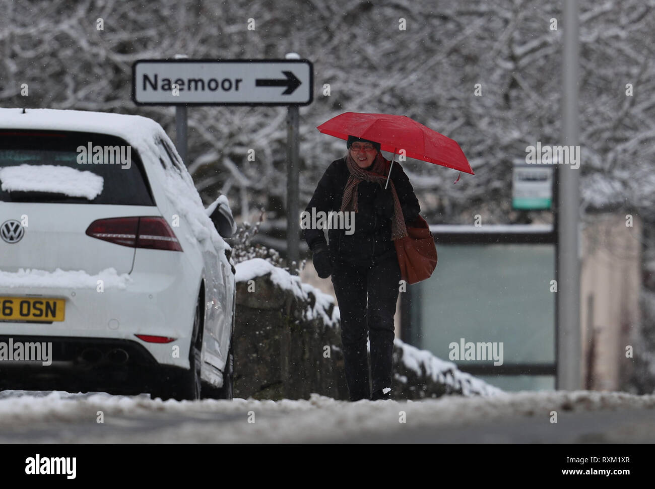 Una donna cammina in condizioni di neve nel tamburo, Fife, come parti della Gran Bretagna sono il risveglio con la neve Domenica come gales sono impostate alla pastella il paese attraverso il giorno. Foto Stock