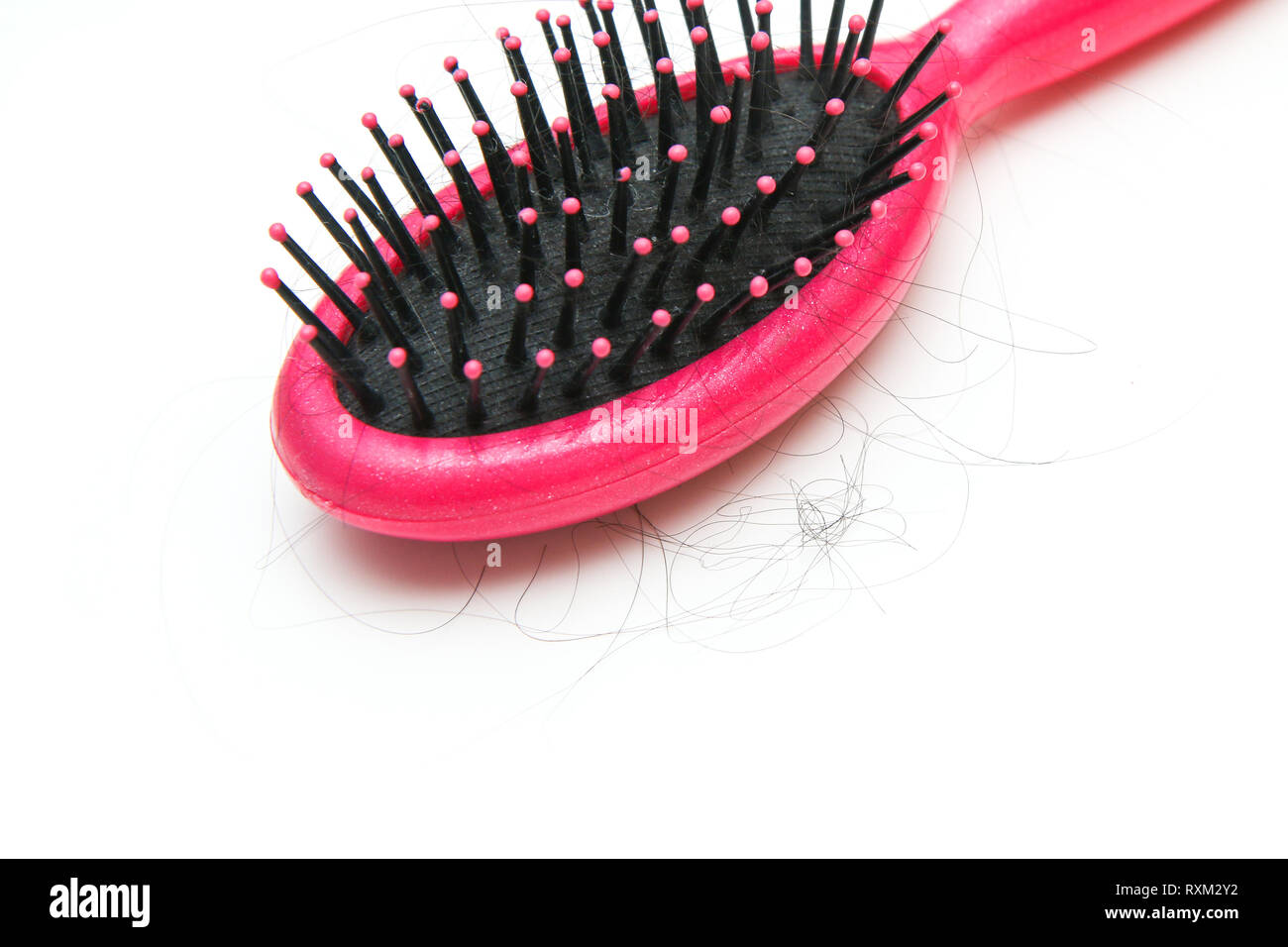 Spazzola per capelli rosa con alcuni peli su di esso. Simboleggia la perdita di capelli di donne. Foto Stock