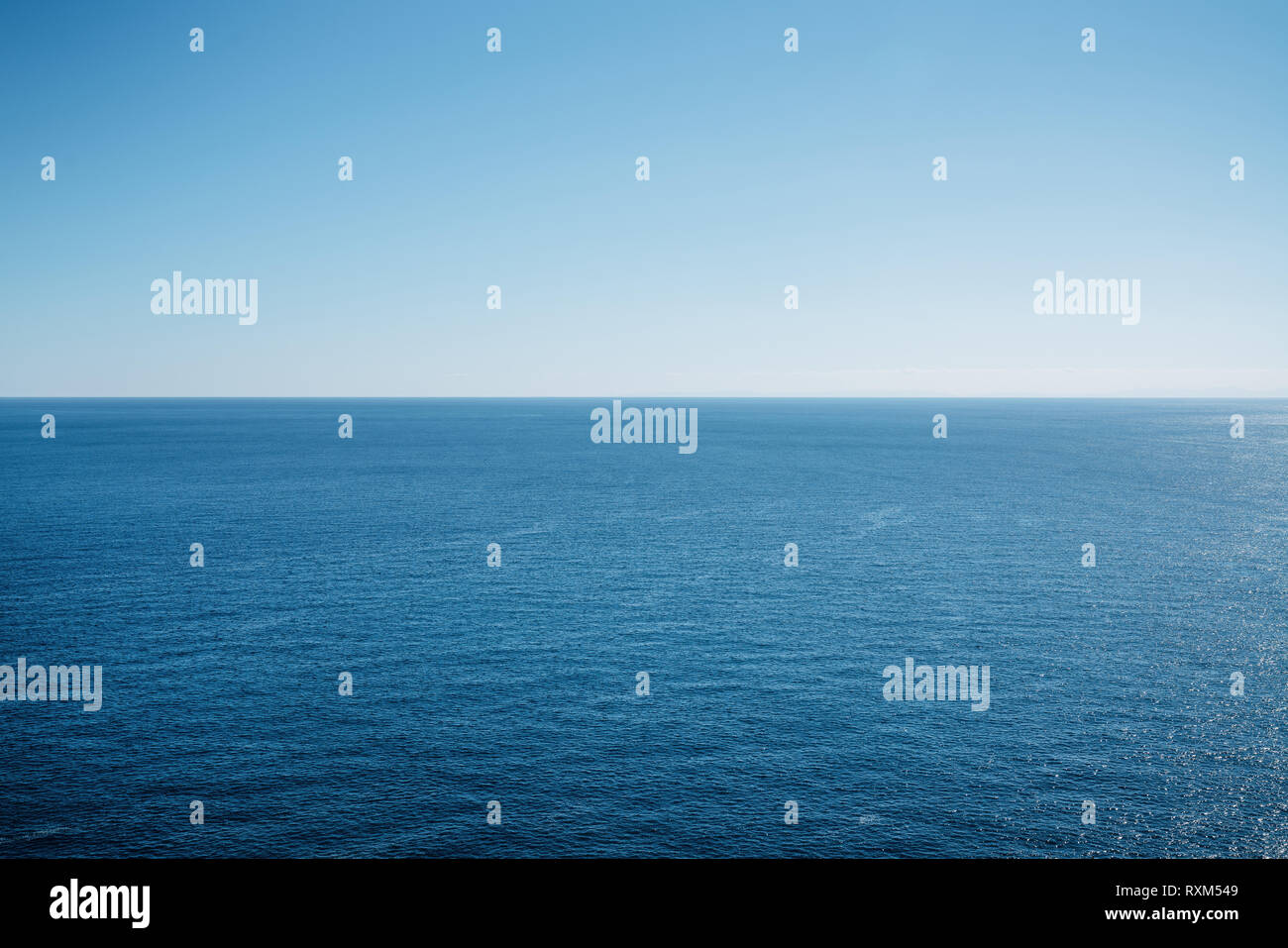 Pulire il cielo blu al di sopra di una superficie blu del mare Foto Stock