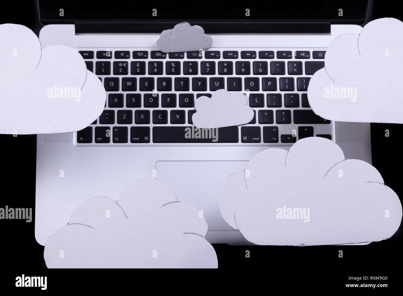 Il cloud computing concetto con intaglio nuvole sopra un computer portatile tastiera su uno sfondo nero Foto Stock