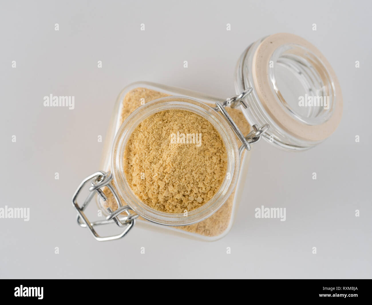 Il lievito nutrizionale dello sfondo. Nutrizionali di lievito inattivo in un barattolo di vetro su sfondo bianco. Copia dello spazio. Vista dall'alto. Il lievito nutrizionale è vegetariano super con sapore di formaggio, per una sana alimentazione Foto Stock