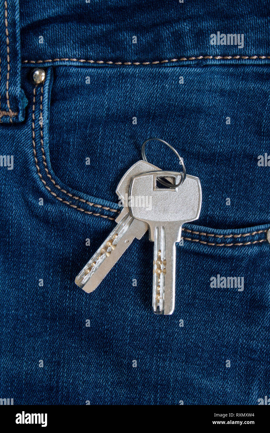 Due chiavi di casa su un portachiavi è giacente in una tasca laterale di jeans blu. Lo stile di vita moderno. Foto Stock