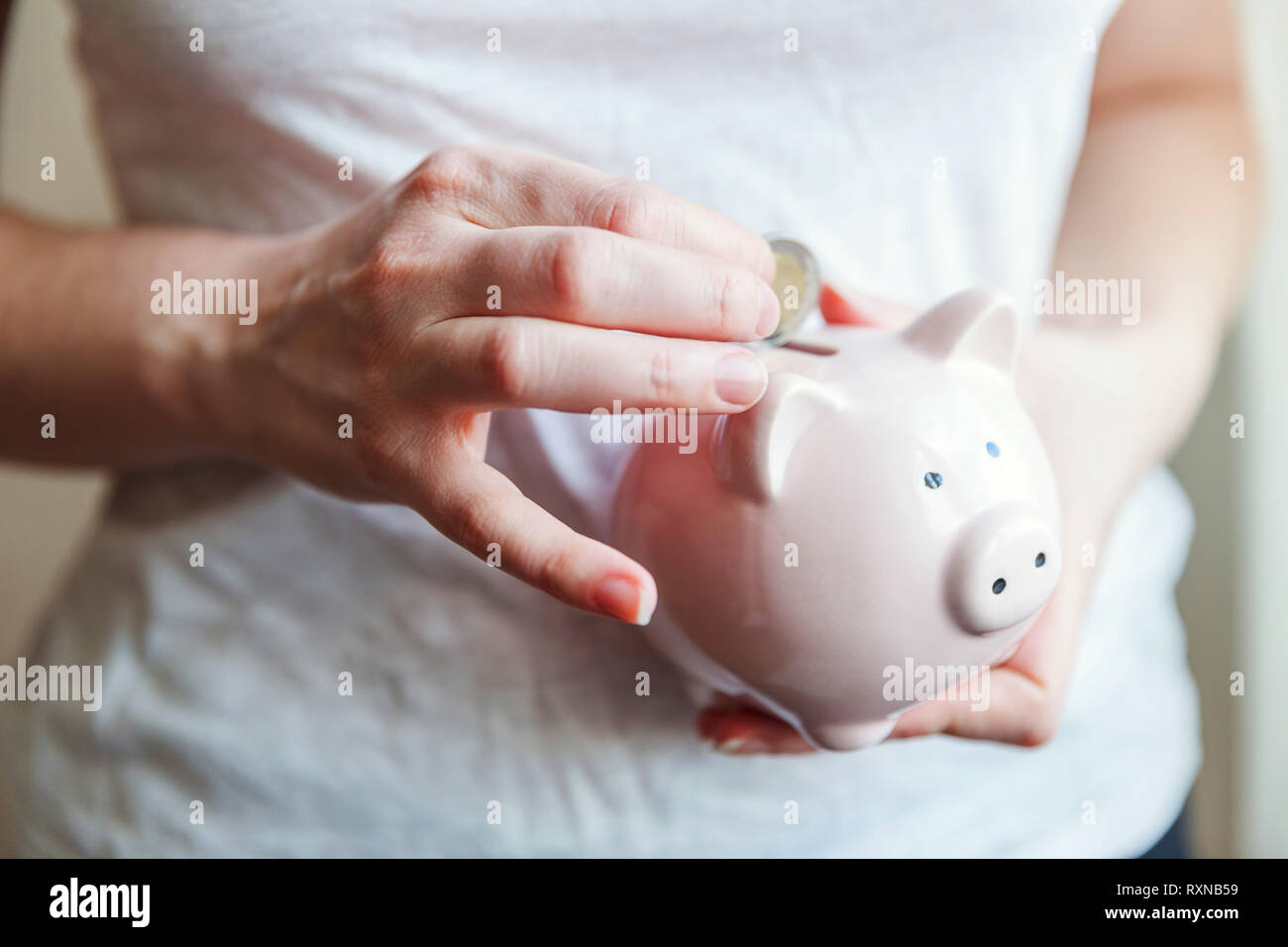 Donna femmina mani rosa salvadanaio e mettere il denaro Euro moneta. Salvataggio di bilancio degli investimenti aziendali pensionamento della ricchezza finanziaria delle banche di denaro concept Foto Stock