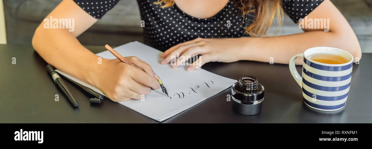 Calligrapher giovane donna scrive una frase sul libro bianco. La Bibbia la frase su amore inscrivendo ornamentali in lettere decorate. La calligrafia, graphic design Foto Stock
