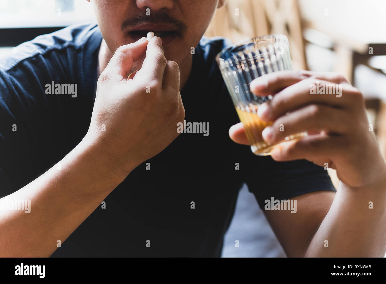 Depressione uomo prendendo pillole con un bicchiere di alcool. Foto Stock