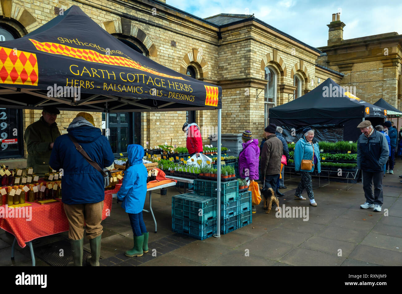 Per coloro che godono di sole primaverile in un angolo riparato del mensile Mercato degli Agricoltori dalla stazione a Saltburn dal Sea North Yorkshire Foto Stock