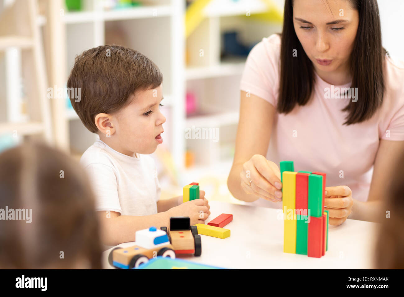 Insegnanti e bambini che giocano insieme con i giocattoli colorati blocchi per costruzioni in età prescolare Foto Stock
