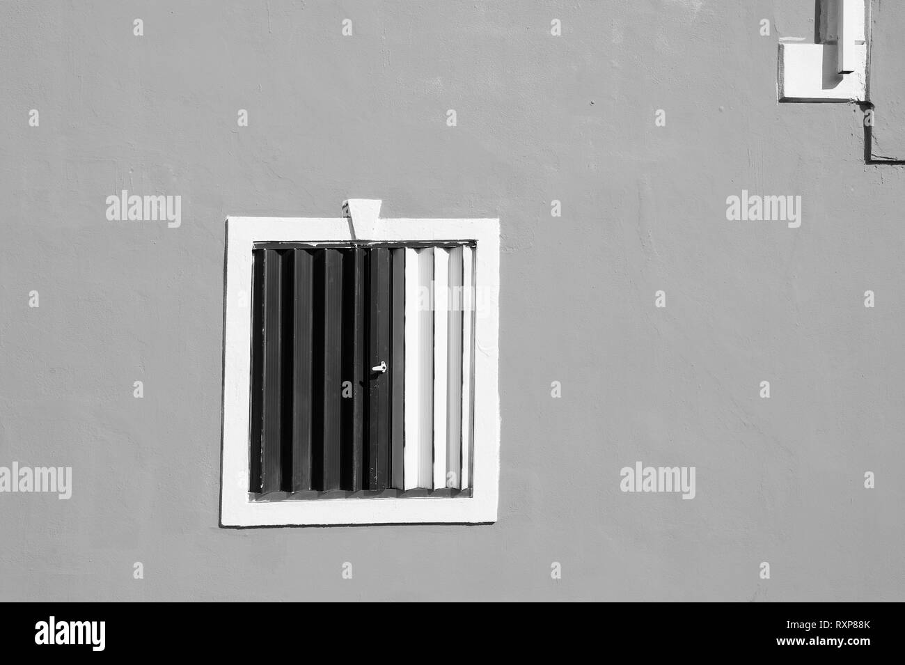 Finestra con ante chiuse e undercolored sulla facciata intonacata parete di edificio residenziale all'aperto sulla giornata di sole su sfondo turchese Foto Stock