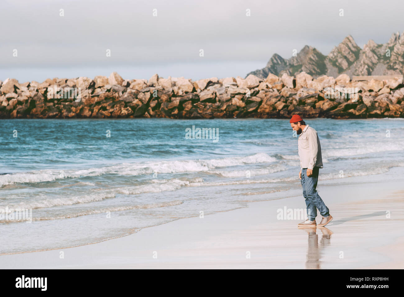 L'uomo traveler godendo di vista oceano sulla spiaggia vuota in viaggio in Norvegia vacanze attive outdoor lifestyle viaggio Foto Stock