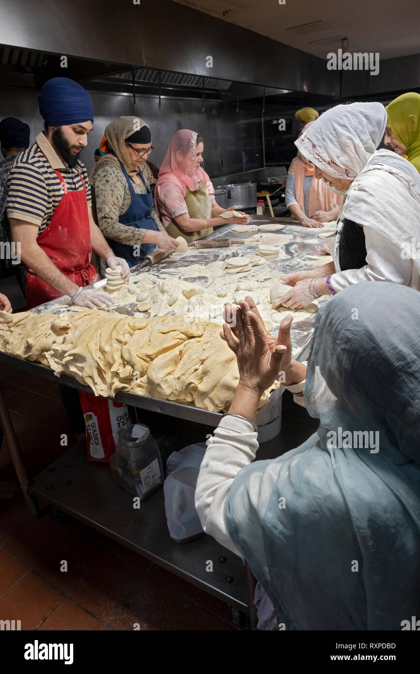 Donne e uomini volontari per un langar, un tempio sikh cucina, preparare roti, una rotonda pane sottile. In South Richmond Hill, Queens, a New York City. Foto Stock