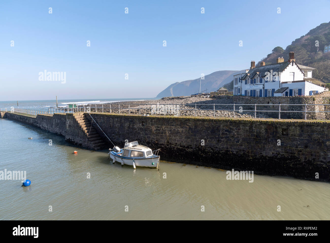 Lynmouth, North Devon, Inghilterra, Regno Unito. Marzo 2019. Lynmouth pier e una piccola barca sul West Lyn fiume dove incontra il Canale di Bristol. Foto Stock