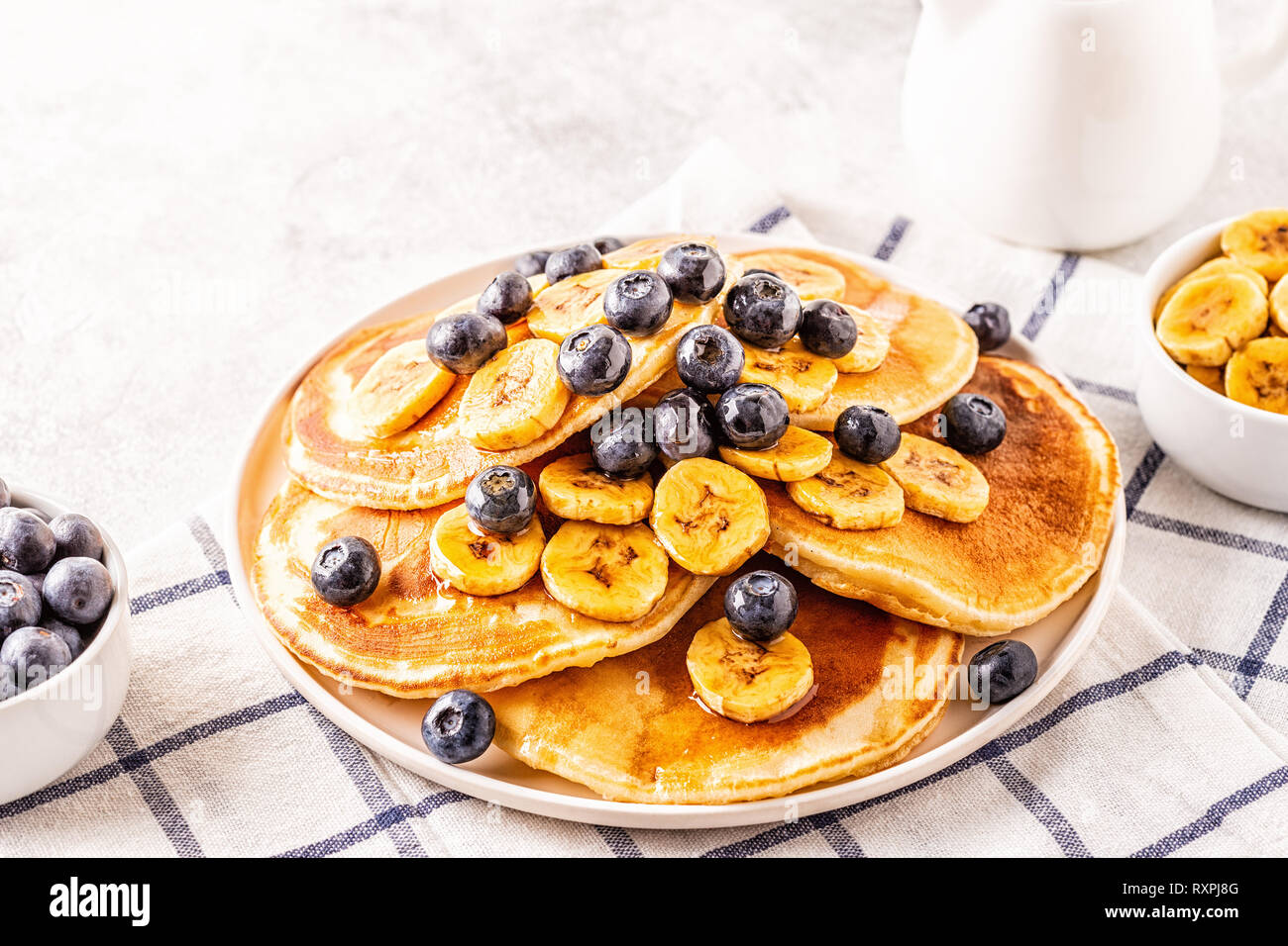 Frittelle di banane, mirtilli sulla piastra bianca, il fuoco selettivo. Foto Stock