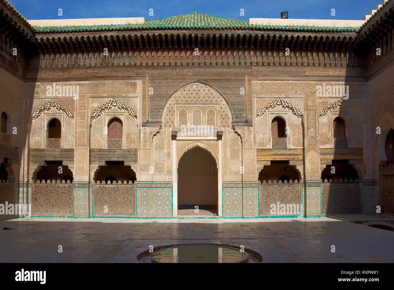 Carving ornati sulle pareti intonacate e sul lavoro di legno nel cortile della storica Madrasa Bou Inania nell'antica medina di Fes in Marocco. Foto Stock