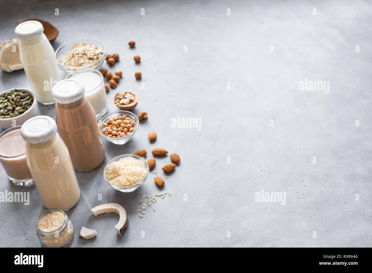 Varie impianto vegana a base di latte e gli ingredienti su grigio, copia dello spazio. Dairy libero sostituto di latte da bere, mangiare sano. Foto Stock