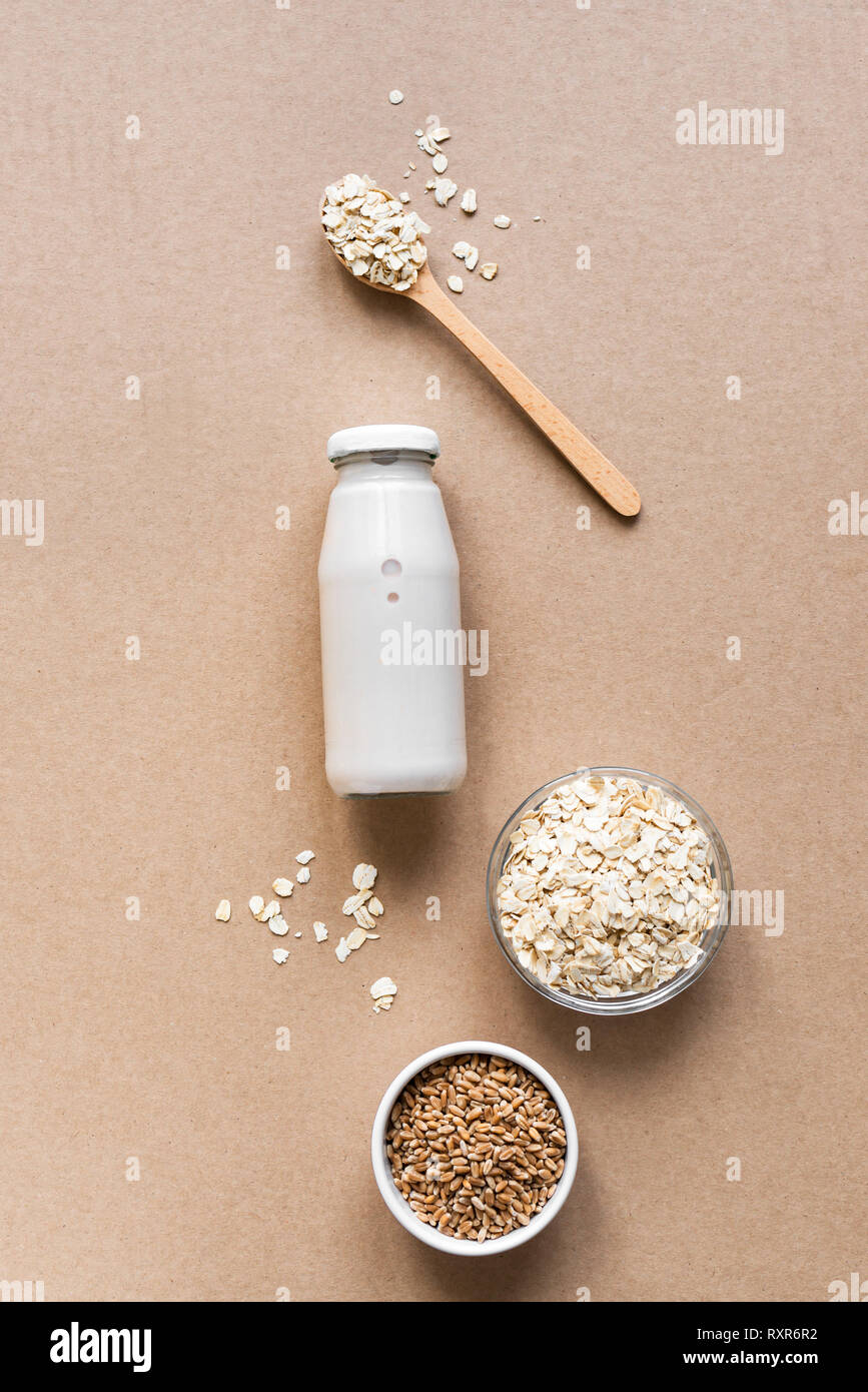 Latte di avena alternativa su sfondo beige, copia spazio, vista dall'alto. Vegano sano sostituto dairy drink gratuito - bottiglia di latte di avena. Foto Stock