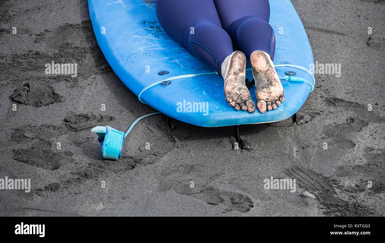 Scuola di Surf. Surfer avente lezione giacente sulla tavola da surf sulla spiaggia. Foto Stock