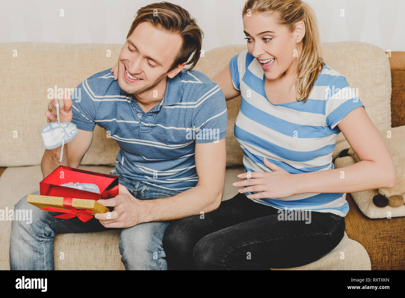 Donna che uomo con scatola di scarpe per bambini, raccontando è incinta. Foto Stock