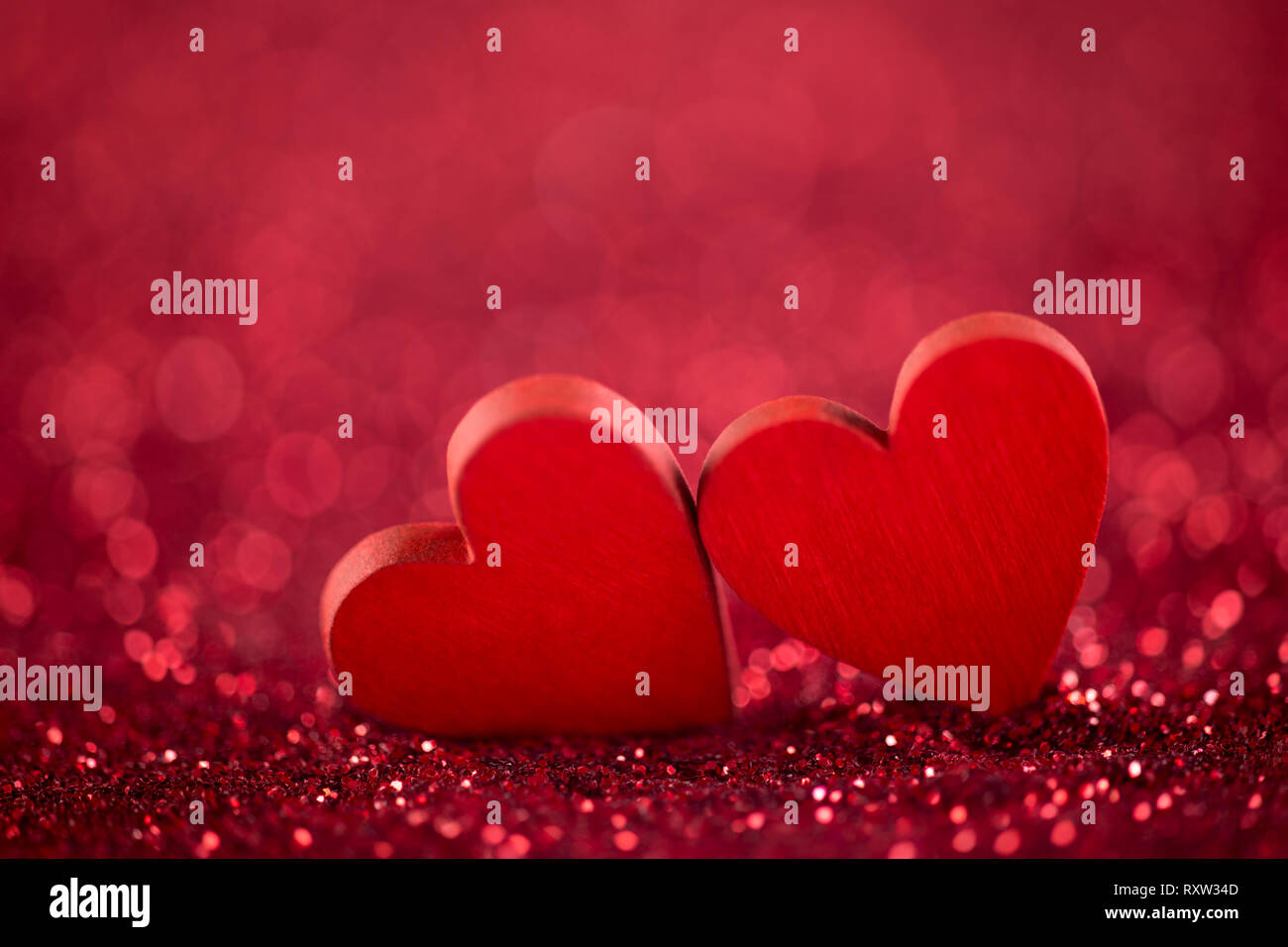 Due cuori rossi su sfondo glitter nel concetto di amore Foto Stock
