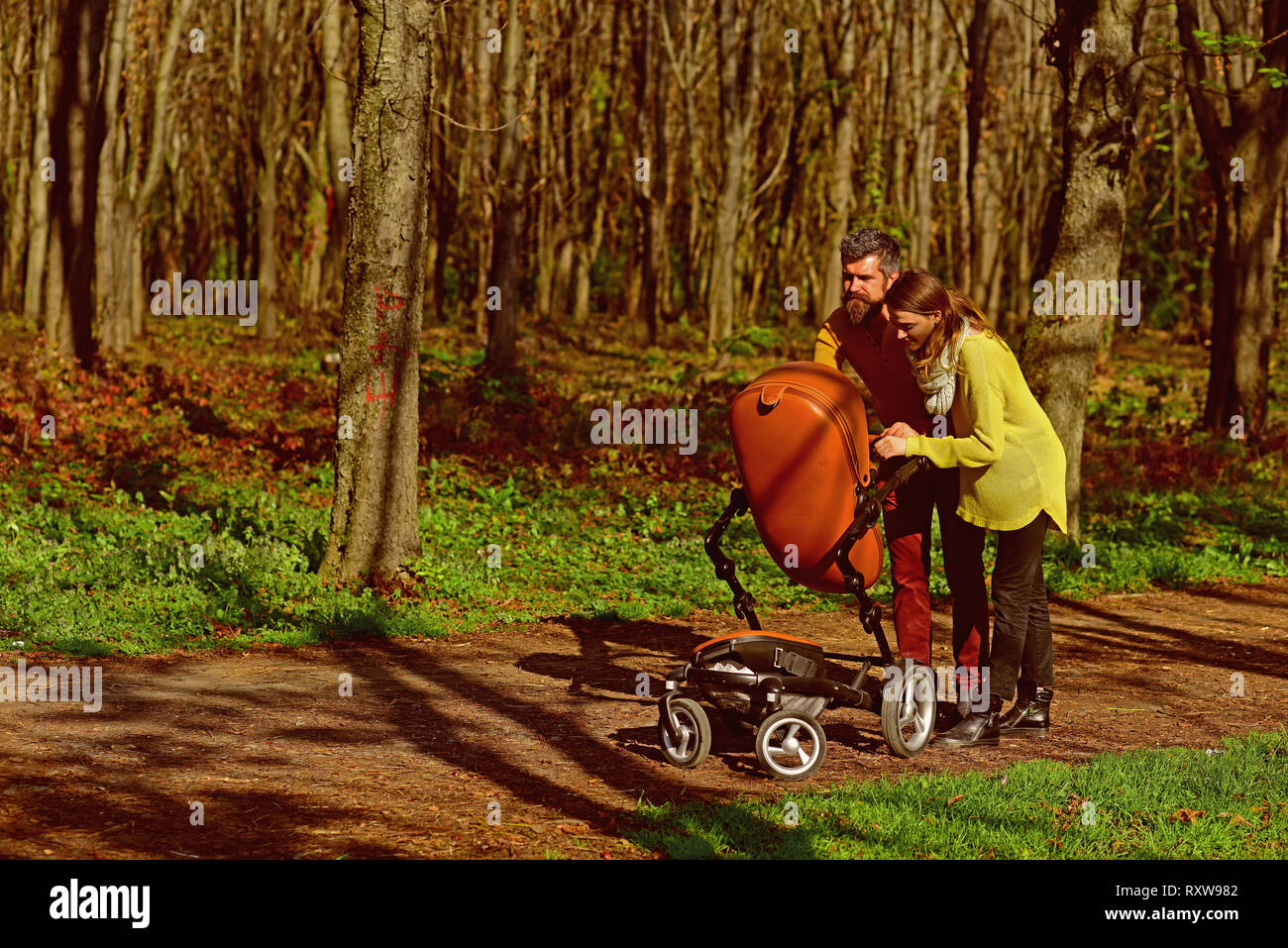 Servizio di baby sitter. Uomo Barbuto e pretty woman baby con baby pram nella primavera del parco. Servizio di custodia dei bambini per i genitori che lavorano Foto Stock