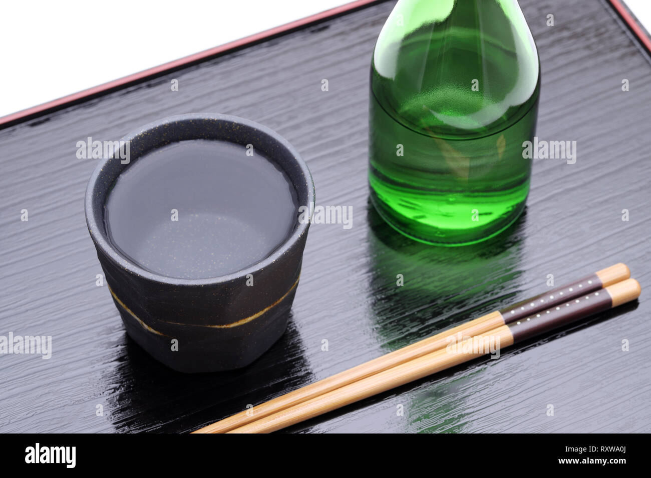 Bottiglia di giapponese shochu e vaso di ceramica sul vassoio in legno, su sfondo bianco Foto Stock