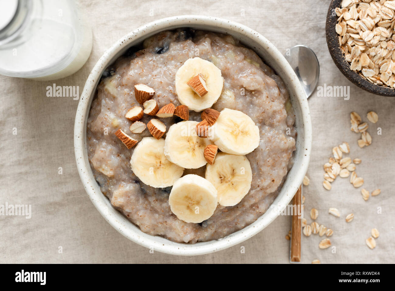 Farina di avena porridge con banana e mandorle. Una sana colazione vegana su lino sfondo. Vista superiore Foto Stock