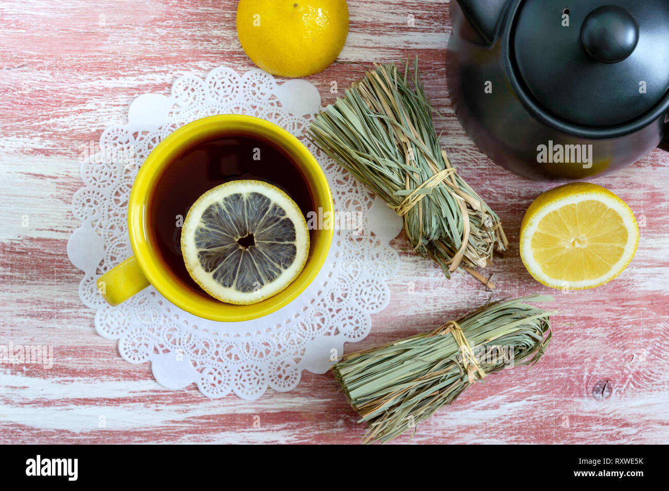 Un mazzetto di asciugare la citronella, limone fresco, teiera e tazza di tè. Ingredienti tè. La cultura del tè bere. Vista dall'alto. Lay piatto. Foto Stock