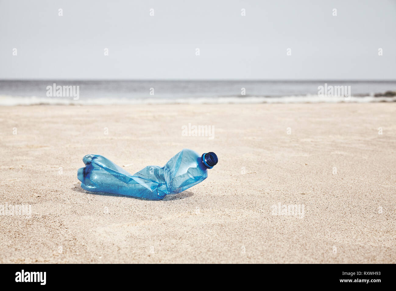Svuotare la bottiglia di plastica su una spiaggia, il fuoco selettivo, tonificazione del colore applicato. Foto Stock