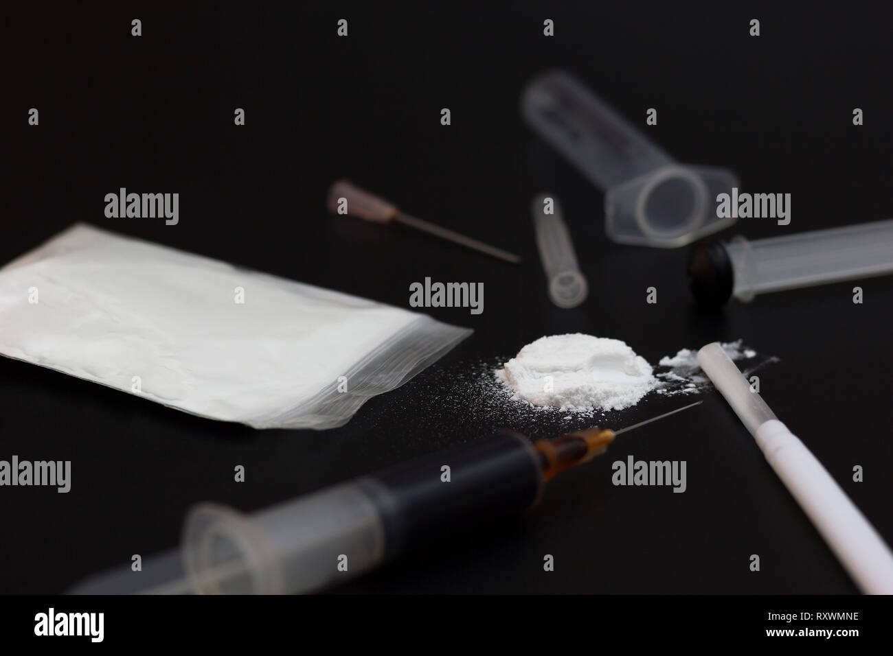 Fake eroina o diacetylmorphine sacco e siringhe affiancate. Chiave di basso coinvolgente sostanza sullo sfondo buio. Foto Stock