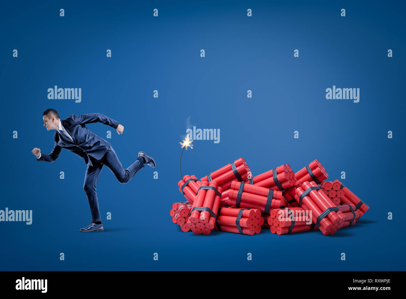 Imprenditore scappando dal pacco di red tnt dynamite bastoni con fusibile illuminato su sfondo blu Foto Stock