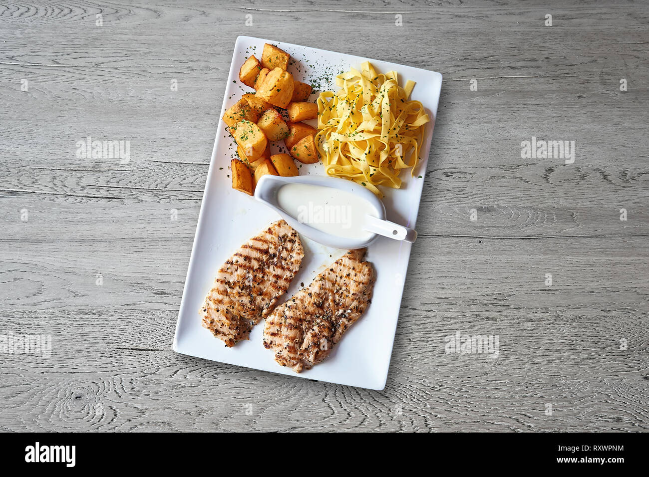 Textured tavolo in legno e la piastra con pollo alla griglia vista da sopra Foto Stock